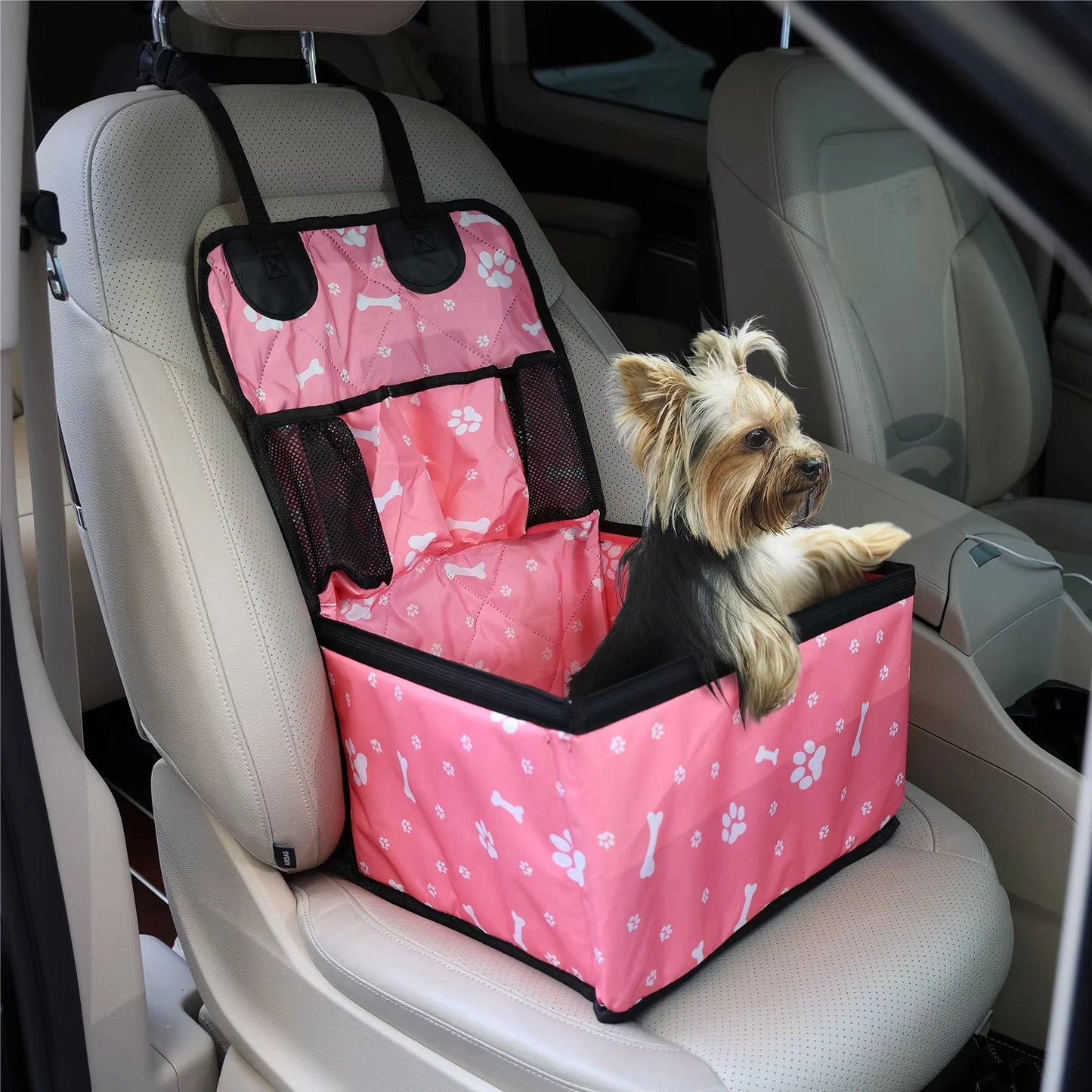 Seggiolino auto booster per cani di piccola taglia disponibile nei colori nero e rosa, posizionato sul sedile anteriore, con tasche laterali e materiale resistente antigraffio.