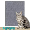 Tappeto tiragraffi autoadesivo di colore grigio scuro applicato sull'angolo di un divano grigio per protezione contro i graffi del gatto, tessuto ritagliabile e resistente.